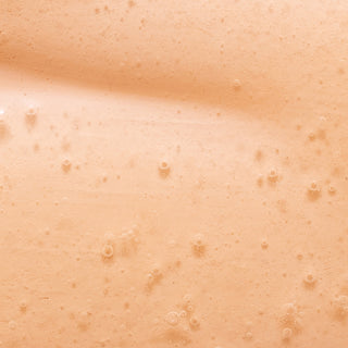 Close-up of a smooth, peach-colored surface with tiny bubbles and subtle texture, resembling the creamy formula of Green Tea Leaves Nourishing Hand Wash.