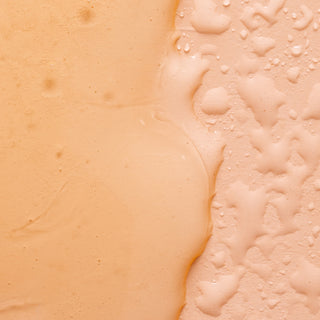 Close-up of a peach-colored liquid surface—one side creamy and smooth, the other bubbly with droplets—reflecting the refreshing cleanse of Lemon Verbena Liquid Hand Soap and Bar Soap from SoF essentials.