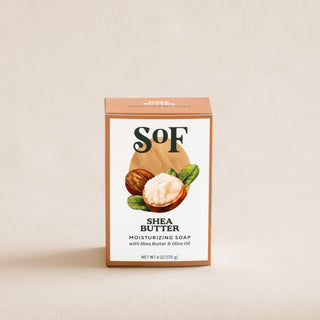 A 6 oz (170 g) Shea Butter Moisturizing Bar Soap with organic shea butter and olive oil, triple-milled and featuring shea nuts and leaves on a cream-colored background.