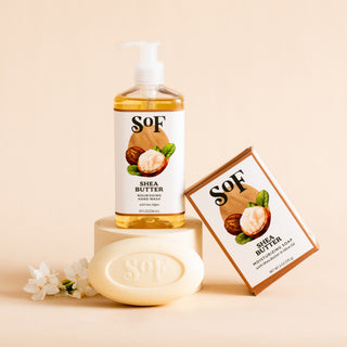 Shea Butter Liquid Hand Soap and Bar Soap, with packaging, are displayed on a beige surface with two white flowers nearby—ideal for gently cleansing and nourishing your skin.